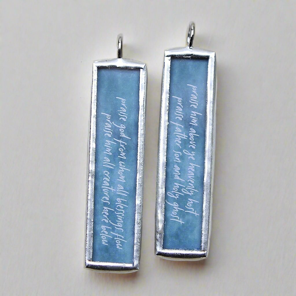 two sided soldered jewelry charm with the doxology on it